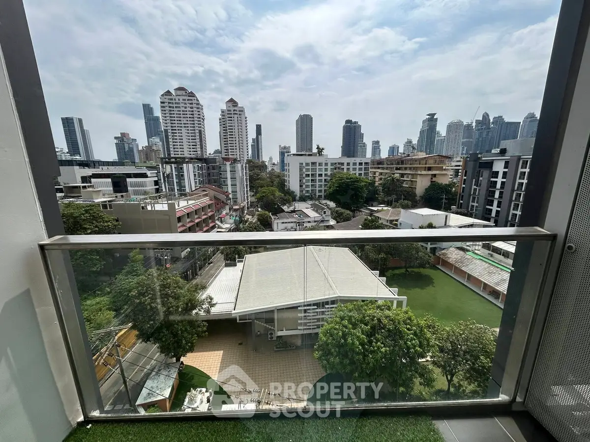 Stunning cityscape view from a high-rise balcony overlooking lush greenery and modern buildings.