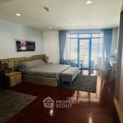 Spacious bedroom with elegant decor and large windows offering natural light.