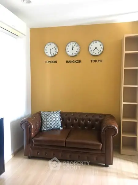 Stylish living room with leather sofa and world clocks on mustard wall