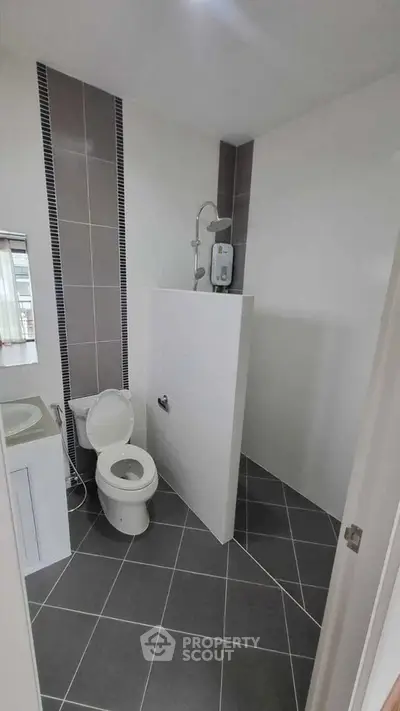 Modern bathroom with sleek design and tiled flooring, featuring a shower and toilet.