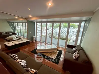 Spacious living room with large windows and modern furniture, offering a serene garden view.