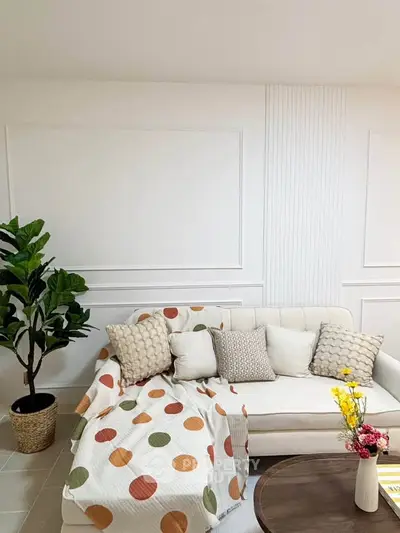 Chic living room with cozy sofa, vibrant decor, and lush plant for modern comfort.