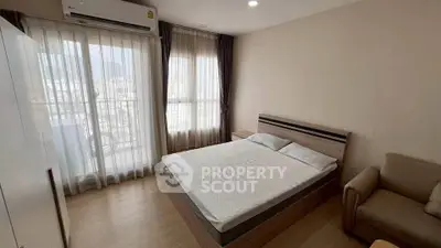 Spacious bedroom with large windows and modern furnishings in a high-rise apartment.