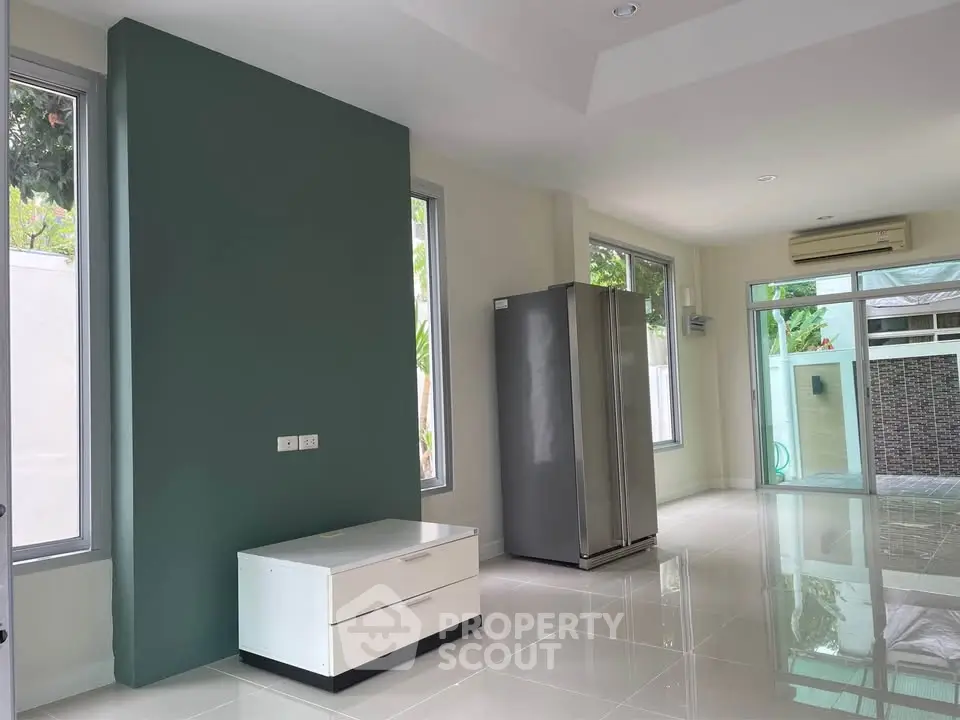 Spacious modern living area with large windows and sleek refrigerator