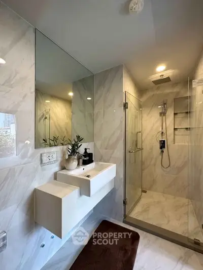 Luxurious modern bathroom with marble tiles and glass shower enclosure