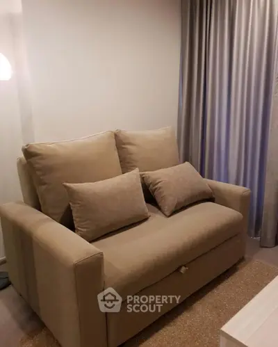 Cozy living room with a stylish beige sofa and elegant curtains, perfect for relaxation.