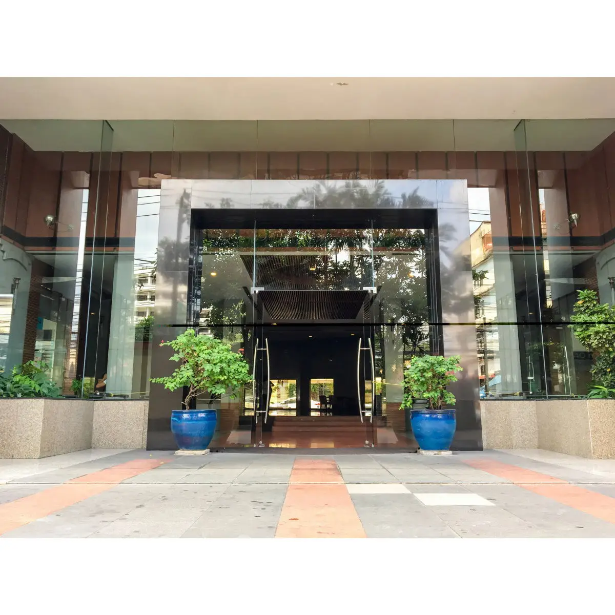 Modern building entrance with glass doors and potted plants, inviting and elegant.