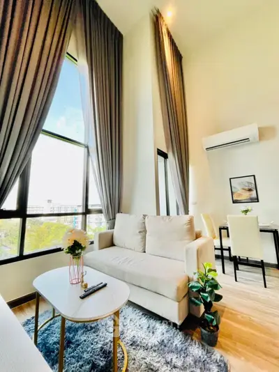 Bright modern living room with high ceilings and large windows, featuring elegant decor and cozy seating.