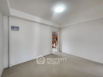 Spacious empty room with tiled flooring and bright lighting, ideal for customization.