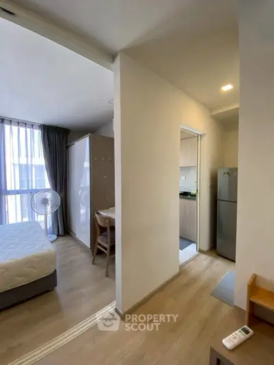 Modern apartment interior with bedroom and kitchen, featuring sleek design and natural light.