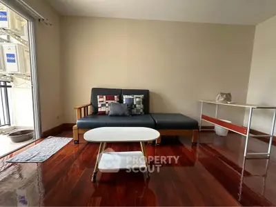 Spacious living room with sleek wooden flooring and modern furniture in a cozy apartment.