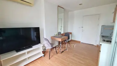Modern living room with TV, dining area, and compact kitchen in a cozy apartment.
