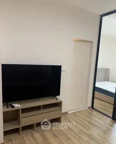 Modern living room with sleek TV stand and glimpse of cozy bedroom