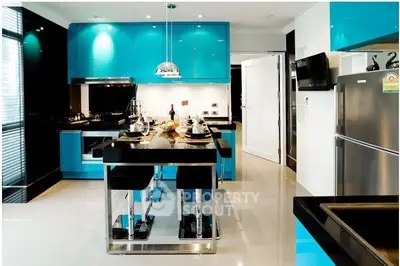 Sleek modern kitchen with vibrant blue cabinets, stainless steel appliances, and a stylish breakfast bar set in a luxurious home.