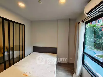 Modern bedroom with large window and air conditioning, offering a cozy and bright living space.