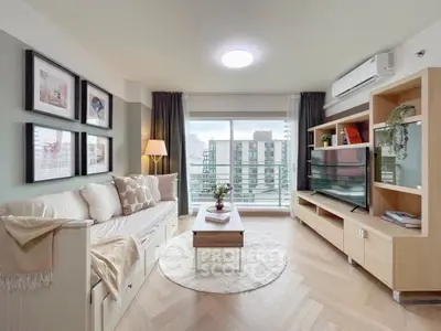 Modern living room with stylish decor and city view, featuring cozy seating and elegant shelving.