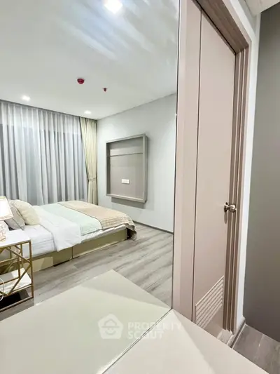 Modern bedroom with elegant decor and large window, featuring a cozy bed and stylish furnishings.