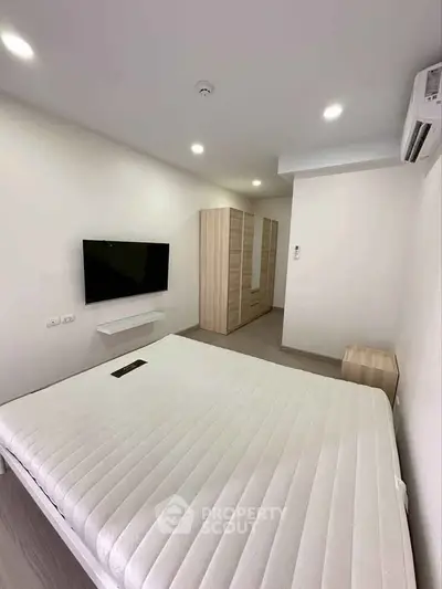 Modern bedroom with minimalist design, featuring a wall-mounted TV and sleek wardrobe.