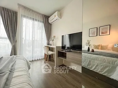 Modern bedroom with sleek design, featuring a cozy bed, wall-mounted TV, and stylish desk under natural light.