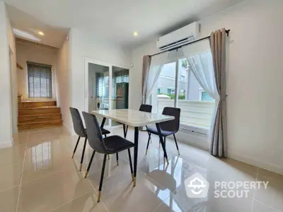 Modern dining area with elegant table and chairs, featuring large windows and natural light.