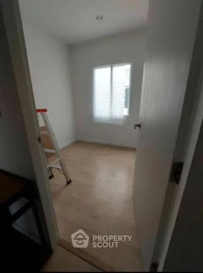 Cozy small room with wooden flooring and natural light, ideal for a study or storage space.