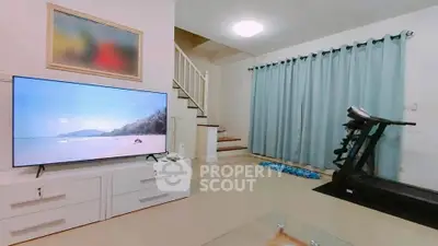 Spacious living room with modern TV and treadmill, perfect for relaxation and fitness.