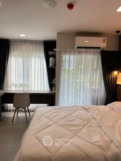 Modern bedroom with natural light, stylish decor, and workspace