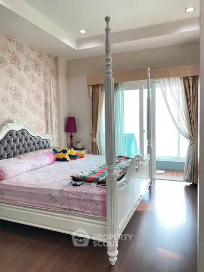 Elegant bedroom with four-poster bed and floral wallpaper, featuring a bright window view.