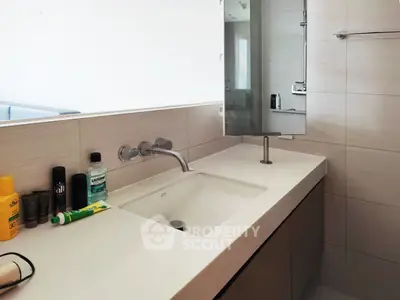 Modern bathroom with sleek sink and mirror, featuring contemporary fixtures and ample counter space.