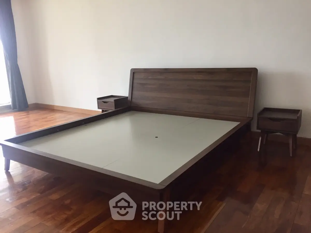 Spacious bedroom with elegant wooden bed frame and matching side tables.