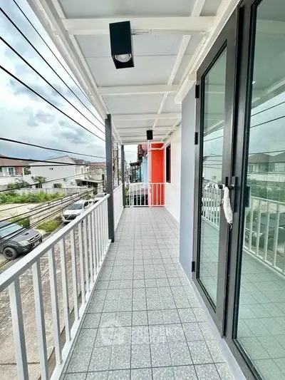Spacious balcony with modern railing and tiled flooring offering street view.