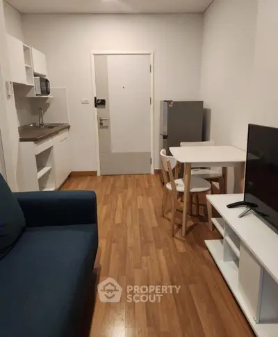 Modern compact living room with kitchenette and dining area in cozy apartment.