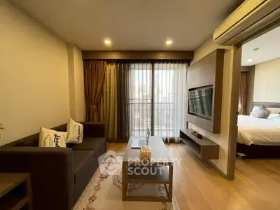 Modern living room with balcony view and cozy bedroom in open layout apartment.