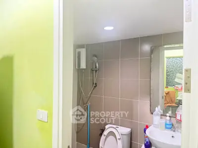 Compact bathroom with modern fixtures and tiled walls, featuring a shower and toilet.