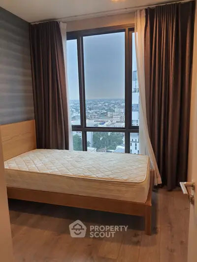 Cozy bedroom with large window offering stunning city views, featuring a comfortable bed and elegant curtains.