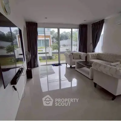 Elegant living room with plush sofas and large windows overlooking a garden view.