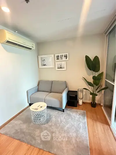 Cozy living room with modern decor, featuring a gray sofa, stylish wall art, and a lush indoor plant.