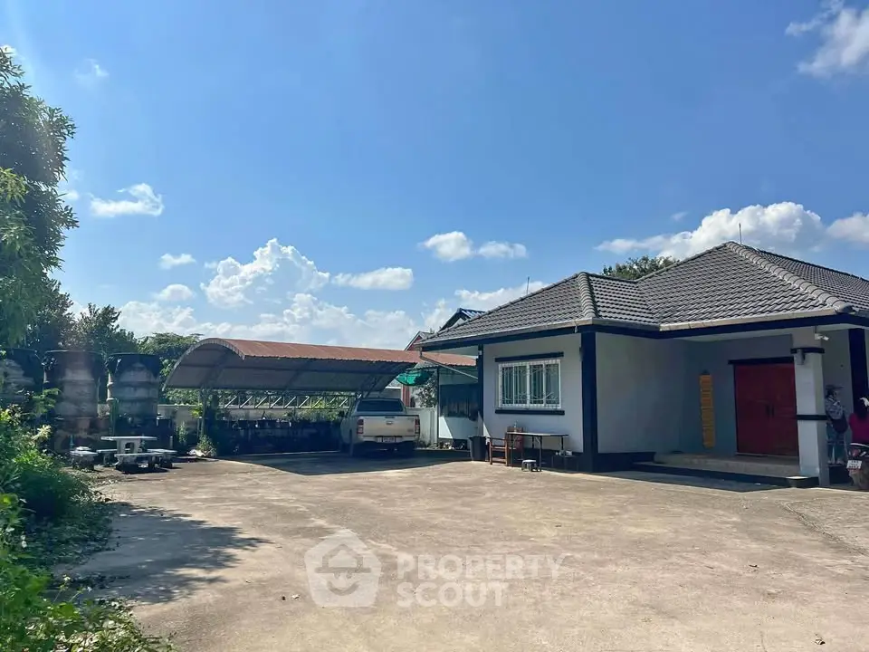 Charming single-story home with spacious driveway and carport under a clear blue sky.