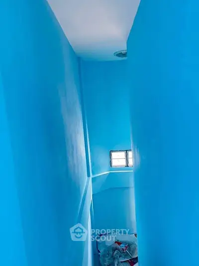 Vibrant blue painted interior space with small window, perfect for creative design ideas.