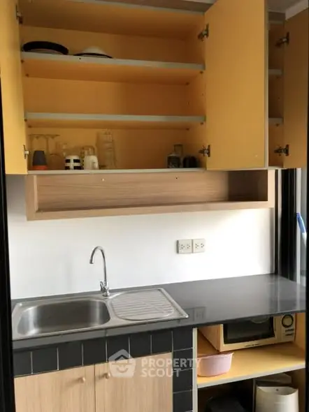 Compact kitchen with open cabinets and modern sink, ideal for small apartments.