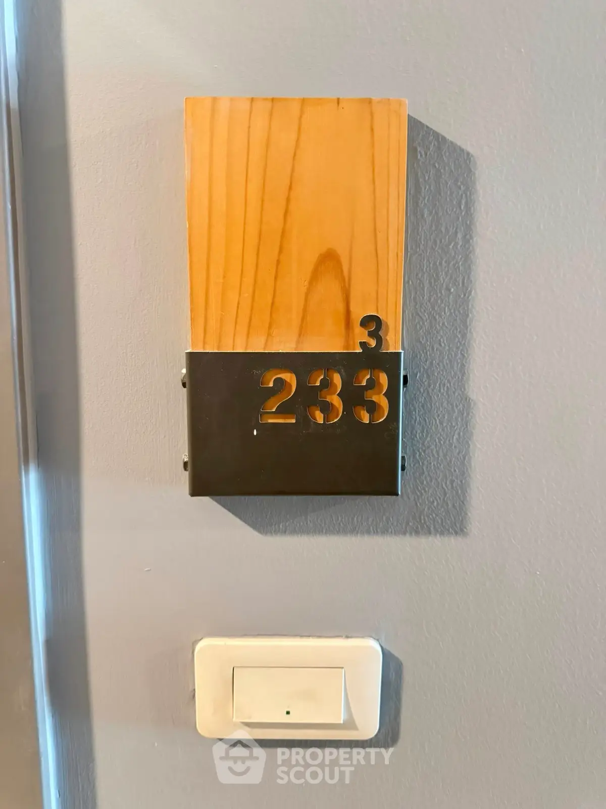 Modern apartment number sign with wooden and metal design on gray wall