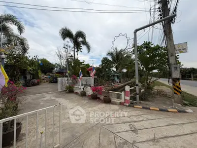 Charming entrance to a tropical garden with flags and lush greenery, perfect for serene living.