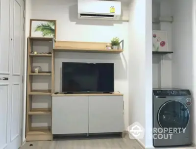 Modern living room with TV, air conditioner, and washing machine in compact space.