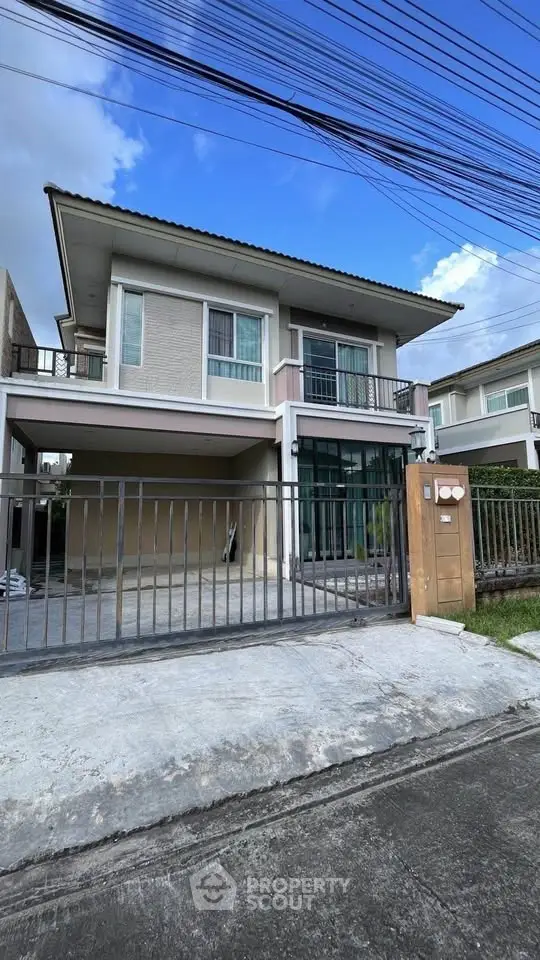 Modern two-story house with gated driveway and contemporary design.