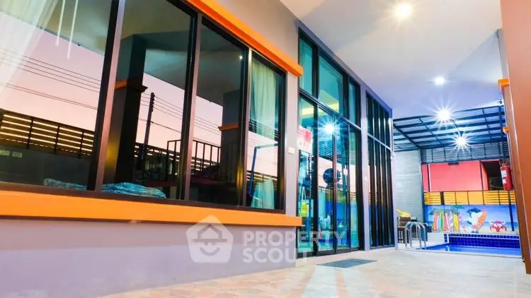 Modern building exterior with glass facade and poolside view at sunset.