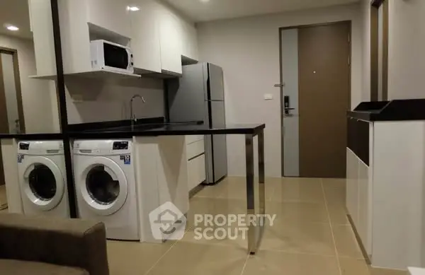 Modern kitchen with washing machines and sleek appliances in open layout.