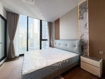 Luxurious bedroom with floor-to-ceiling windows offering stunning city views, modern design and elegant decor.