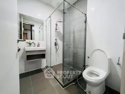 Modern bathroom with glass shower and sleek fixtures in contemporary home.