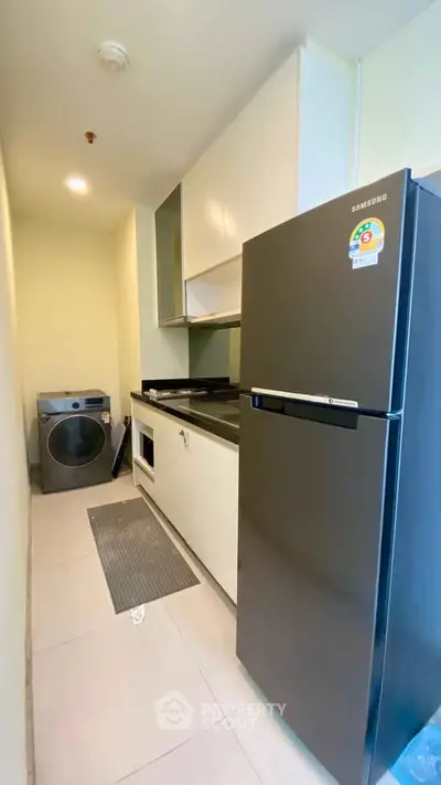 Modern kitchen with sleek appliances and compact design, featuring a fridge and washing machine.