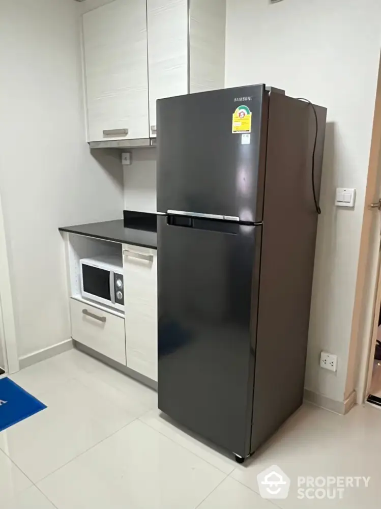 Modern kitchen with sleek fridge and microwave in compact layout